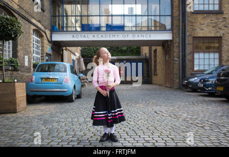 Ein junges Mädchen posiert mit einer roten Rose nach ihrem Grad 1 Ballett Prüfung außerhalb der Royal Academy of Dance in London Stockfoto