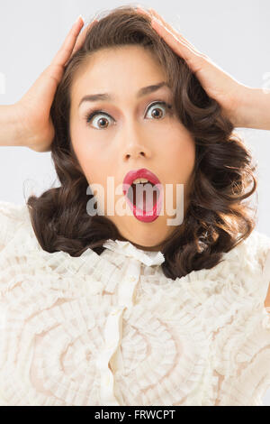 Schöne junge Frau in weißer Bluse und blauen Jeansrock, Schock, mit Händen, Kopf zeigen. Stockfoto