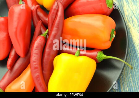 Vielzahl von verschiedenen Paprika auf schwarzem Teller Stockfoto