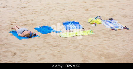 Junge Frau, Sonnenbaden am Strand tragen von Kopfhörern und Handy zu betrachten. Stockfoto