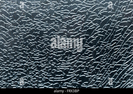 Zerbrochenes Glas mit Rissen und Fragmente über dunkelblauen Hintergrund. Nahaufnahme Fototextur Stockfoto