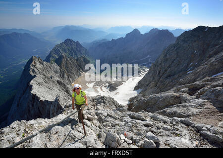 Frau aufsteigend auf Klettersteig, Zugspitze, Gletscher Hoellentalferner im Hintergrund, Wetterstein-Gebirge, Upper Bavaria, Bavaria, Germany Stockfoto