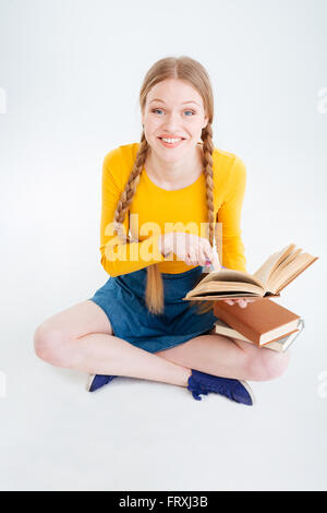 Studentin, die sitzen auf dem Boden mit Buch und Blick in die Kamera Lächeln Stockfoto