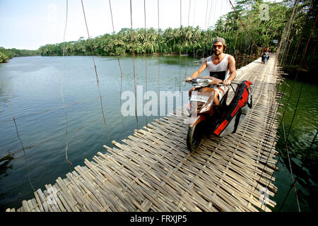 Mann auf einem Motorroller, vorbei an einer Hängebrücke, Jakarta, Java, Indonesien Stockfoto