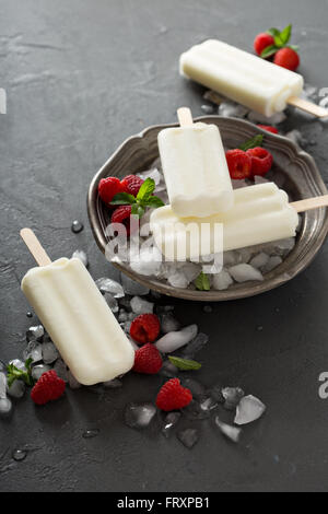 Kokosnuss-Eis mit Himbeeren auf schwarzem Hintergrund Stockfoto