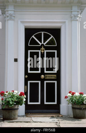 Rote und weiße Geranien in alte hölzerne Fässer beiderseits eine schwarz + weiß Haustür von einem georgianischen Stadthaus Stockfoto