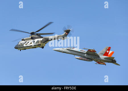 Aerospatiale Super Puma Militärhubschrauber T-316 der Schweizer Luftwaffe fliegt in Formation mit einer F/A - 18 C Hornet Kämpfer Stockfoto