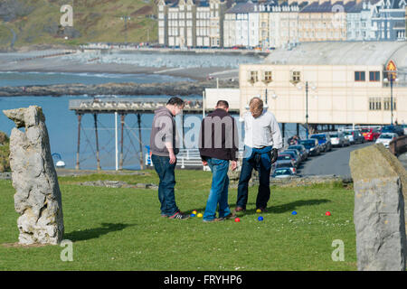 Aberystwyth, Wales, UK. 25. März 2016.  UK-Wetter: drei Männer Boule spielen, machen die meisten täglich feine Sonnenstrahlen am Karfreitag, am Anfang von Ostern Wochenende von Feiertagen, Amngst die Menhire auf dem Gelände des Schlosses in Aberystwyth im Westen wales Küste UK.   Die Wettervorhersage für das Wochenende ist der sich verschlechternden Bedingungen, gipfelnd in Stürme und Starkregen für Ostermontag Credit: Keith Morris/Alamy Live-Nachrichten Stockfoto