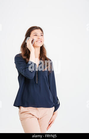 Fröhliche attraktive junge Frau stehen und reden über Handy auf weißem Hintergrund Stockfoto