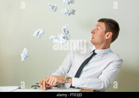 Zerknittertes Papier fliegen ins Gesicht junger Geschäftsmann Stockfoto