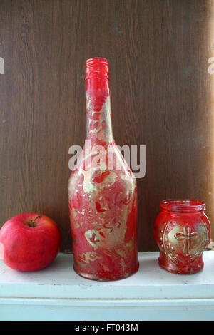 Dekoration für Haus, hergestellt aus Glasflasche bemalt in rot und Gold mit süßen roten Apfel Stockfoto