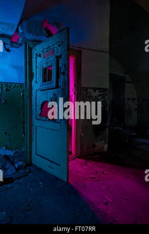 Abstrakte farbige Lichtmalerei in verlassene sowjetische Bunker. Rosa helles Licht durch defekte Türen Stockfoto