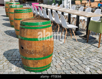 vor langen Tisch und Stühle angeordnet alten Holzfässern für Abendessen im freien Stockfoto