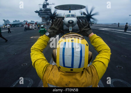 160305-N-GZ947-151 SOUTH CHINA SEA (5. März 2016) - Aviation Boatswain Mate (Handling) Airman Leah Wade leitet ein E - 2 C Hawkeye, das Flugdeck goldenen Falken von Airborne frühe Warnung Squadron (VAW) 112 auf USS John C. Stennis' (CVN-74) zugewiesen. Bereitstellung einer bereit Kraft unterstützende Sicherheit und Stabilität in der Indo-Asien-Pazifik, ist Stennis als Teil der großen grünen Flotte auf einer regelmäßig stattfindenden 7. Flotte Bereitstellung tätig. (Foto: U.S. Navy Mass Communication Specialist 3. Klasse Kenneth Rodriguez Santiago / veröffentlicht) Stockfoto