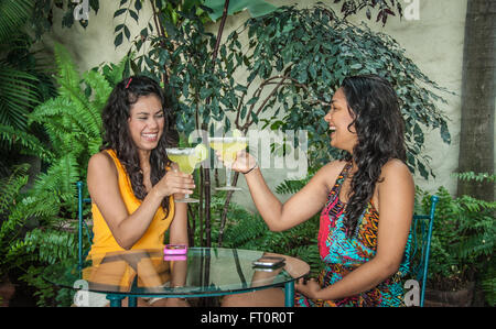 2 junge Hispanic Frauen Toast mit Margarita Getränke auf tropischen Innenhof - Puerto Vallarta, Mexiko #613PV Stockfoto
