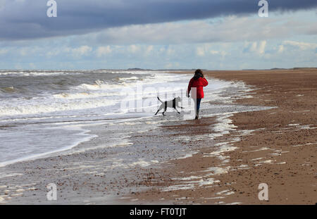 Frau und ihr Hund Dornweiler Strandleben an der North Norfolk Küste genießen. Stockfoto