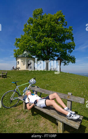 Weibliche Radfahrer ruht in der Nähe einer Kapelle, Toerwang, Samerberg, Oberbayern, Deutschland Stockfoto