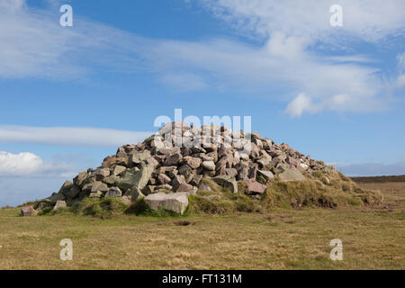 Ein Stein Cairn erstellt auf einem Hügel, wo die Wanderer einen Stein auf den Haufen hinterlassen haben, durchgeführt von unten. Stockfoto