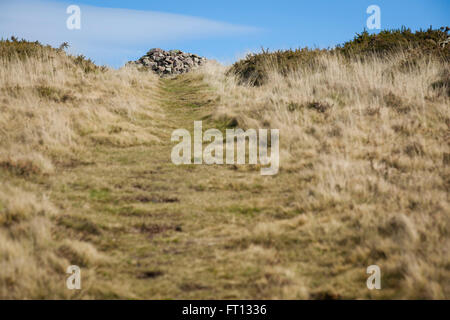 Ein Stein Cairn erstellt auf einem Hügel, wo die Wanderer einen Stein auf den Haufen hinterlassen haben, durchgeführt von unten. Stockfoto