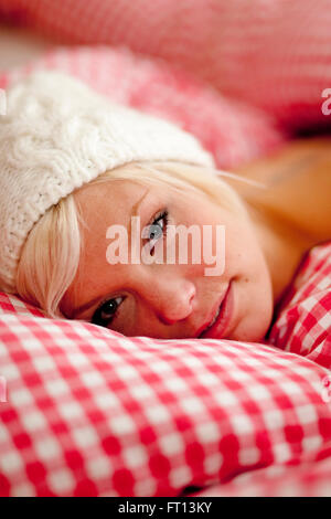 Junge Frau trägt eine Mütze im Bett liegend Stockfoto