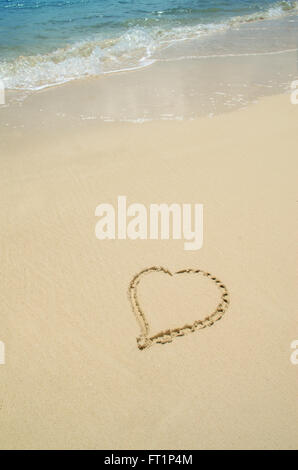 Ein Herz zieht es in den Sand des Strandes im Paradies mit Textfreiraum Stockfoto