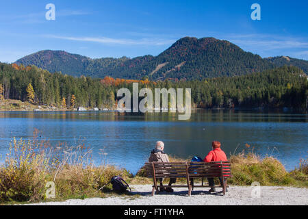 Ältere Touristen auf Bank, Blick auf See Hintersee in den Bayerischen Alpen, Berchtesgadener Land, Oberbayern, Deutschland Stockfoto