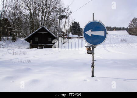 Blaue Richtung Verkehrszeichen am Ende des Skiliftes in verschneiten Bergen Stockfoto