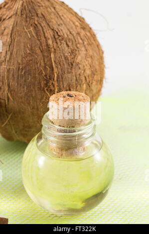 Kokosnuss-Öl in eine Flasche mit frischen Kokosnuss im Hintergrund Stockfoto
