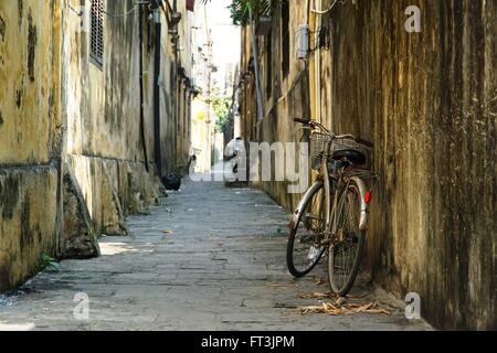 Ein einsamer rostigen Fahrrad lehnt an einer Wand in einer Gasse in Hoi an, Vietnam. Stockfoto