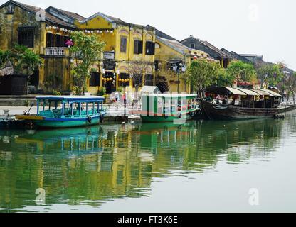 Touristischen Boote vertäut am Flussufer in Hoi an, Vietnam. Gebäude im Kolonialstil säumen die Straßen. Stockfoto
