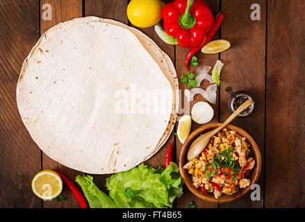 Zutaten für Burritos wraps Hühnerfleisch, Mais, Tomaten und Paprika auf hölzernen Hintergrund. Ansicht von oben Stockfoto