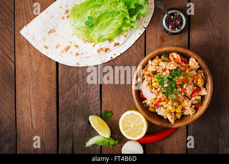 Zutaten für Burritos wraps Hühnerfleisch, Mais, Tomaten und Paprika auf hölzernen Hintergrund. Ansicht von oben Stockfoto