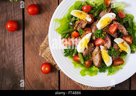 Warmer Salat mit Geflügelleber, grüne Bohnen, Eiern, Tomaten und Balsamico-Dressing. Ansicht von oben Stockfoto