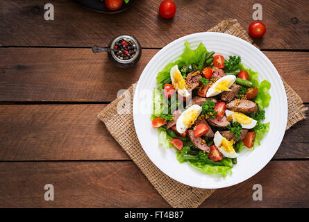 Warmer Salat mit Geflügelleber, grüne Bohnen, Eiern, Tomaten und Balsamico-Dressing. Ansicht von oben Stockfoto