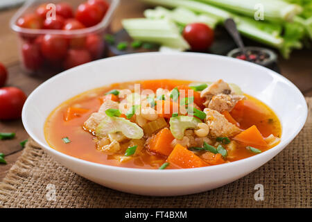 Tomaten-Hühnersuppe mit Kürbis, Bohnen und Sellerie in Schüssel weiß Stockfoto
