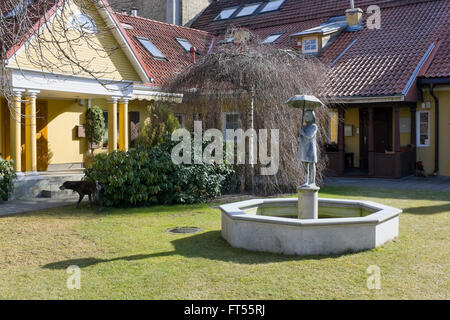 VILNIUS, Litauen - 13. März 2016: Der Brunnen und das Mädchen Skulptur mit einem Regenschirm auf dem Hof des Holzhauses auf T Stockfoto
