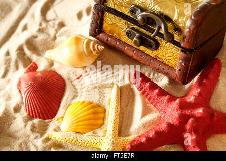Schatztruhe mit Muscheln auf Sand Hintergrund Stockfoto