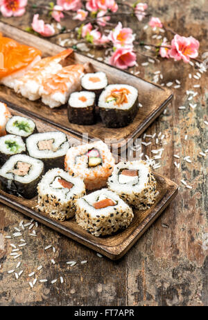 Sushi, Maki, Sashimi und Sushi Rollen auf hölzernen Hintergrund mit Frühlingsblumen Stockfoto