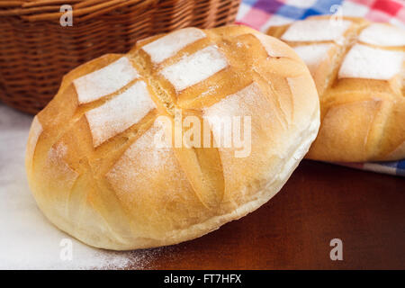 Runder Laib Brot mit Küche Lappen, Mehl und geflochtenen Korb Stockfoto