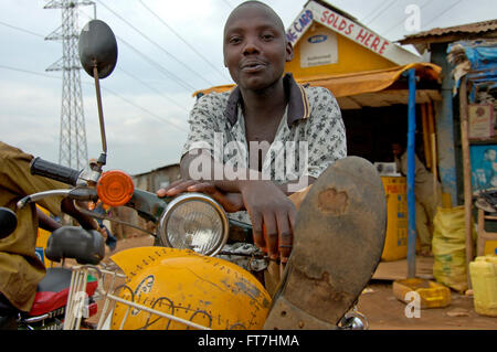 Kampala, Uganda-11 April 2017. Die Art und Weise Menschen leben in Uganda. Junge auf seinem Roller. Stockfoto