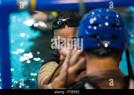 CBP-Büro für Luft- und Lotsen geschult Inversion Wasser, das einen Absturz im Freiwasser und wie man sicher verlassen das Flugzeug während im National Air Training Center in Oklahoma City, Oklahoma untergetaucht simuliert. Ein Kursleiter überprüft Sicherheitsausrüstung für einen Studenten. Foto von James Tourtellotte. Stockfoto