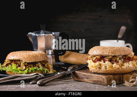 Zwei Bagels mit Eintopf Rindfleisch, frischem Salat, Speck, Rührei und gebratenen Zwiebeln serviert auf Vintage Metalltablett und Holz hacken b Stockfoto