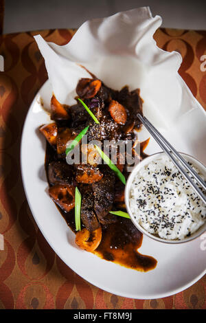 Asiatische Schale - Rindfleisch in schwarzer Pfeffer-Sauce, mit Reis, schoss auf Vintage Sessel Stockfoto