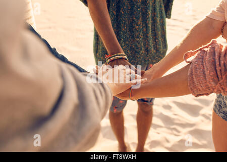 Freunde am Strand Hand zusammenzustellen. Gemischtrassigen Gruppe von jungen Leuten mit Händen im Stapel am Strand. Stockfoto