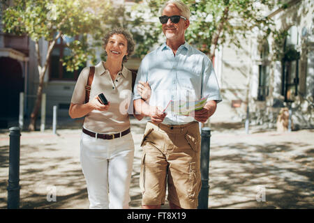 Älteres Paar zu Fuß durch die Stadt im Besitz einer Karte. Älteres Paar mit einer Karte der Stadt unterwegs. Stockfoto