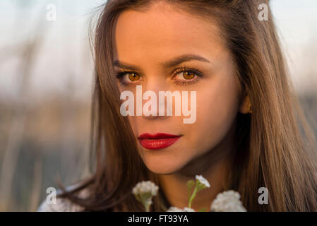 Herbstlook. Porträt von ein schöne Teenager-Mädchen mit kleinen Blumenstrauß in einem Herbst Feld. Mädchen hat braune Augen und Haare und rote Lippen Stockfoto