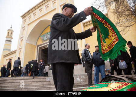 Muslim kauft einen Teppich vor dem Freitagsgebet am Eingang zu den größten in China ID-Kah Moschee in Kashgar Stadt Stockfoto