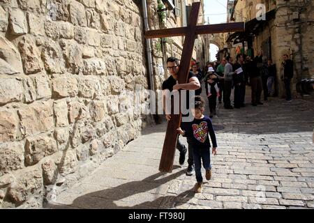 Jerusalem. 25. März 2016. Ein christlicher Pilger trägt ein hölzernes Kreuz entlang der Via Dolorosa (Weg des Leidens) in der Altstadt von Jerusalem während der Karfreitags-Prozession am 25. März 2016. © Muammar Awad/Xinhua/Alamy Live-Nachrichten Stockfoto