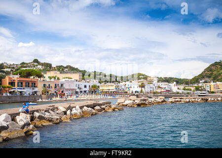 Lacco Ameno, Italien - 11. August 2015: Sommer am Meerblick auf Lacco Ameno, Fischer sitzt auf steinernen Wellenbrecher. Ischia Stockfoto