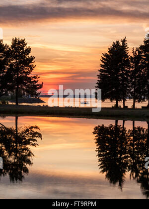 Gespiegelte Sonnenuntergang. Glasige stilles Wasser spiegelt die leuchtenden Orangen eines Sonnenuntergangs über dem Ottawa-Fluss und Teich in Andrew Haydon Stockfoto